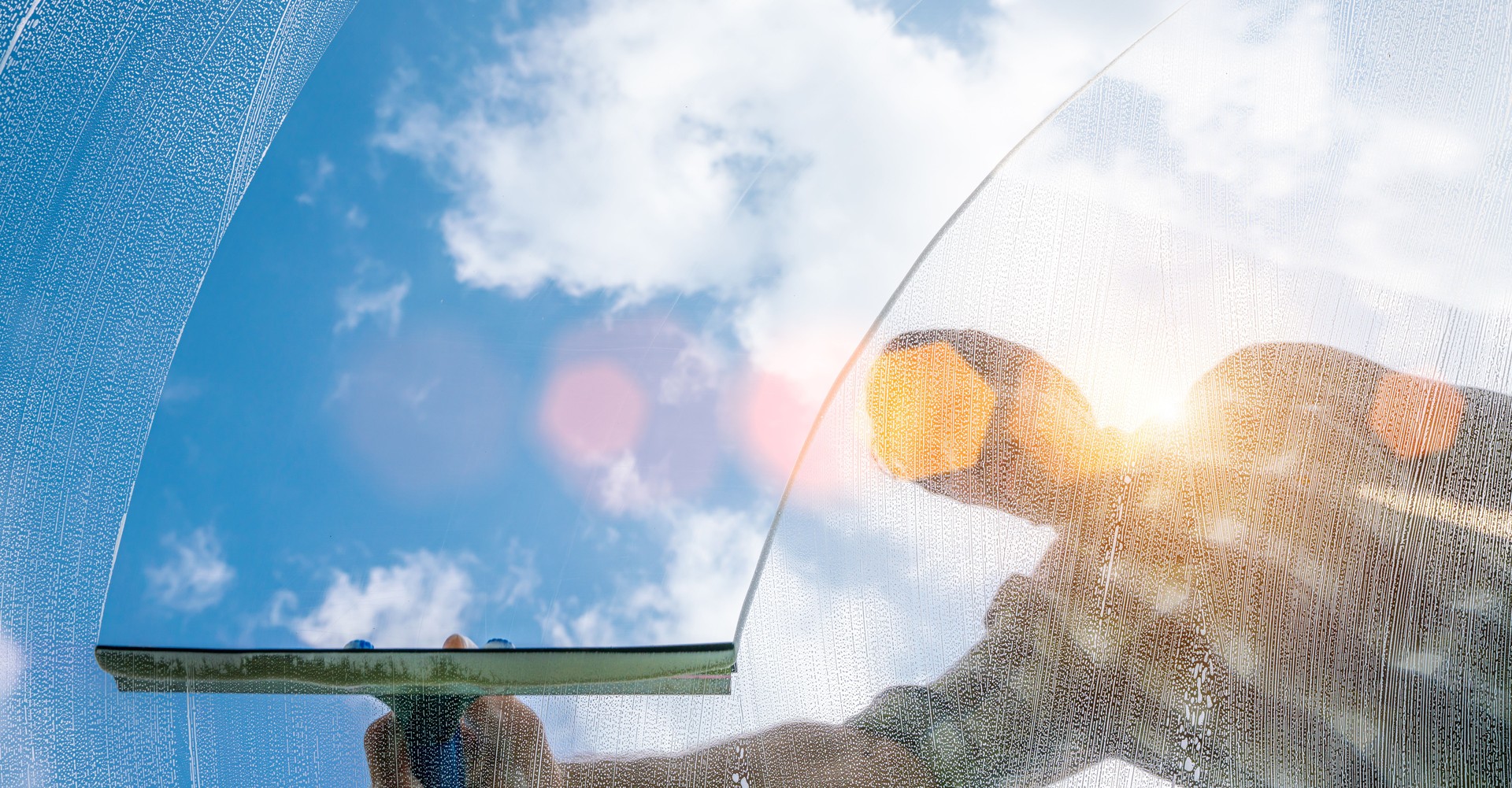 window cleaner cleaning window with squeegee and wiper on a sunny day